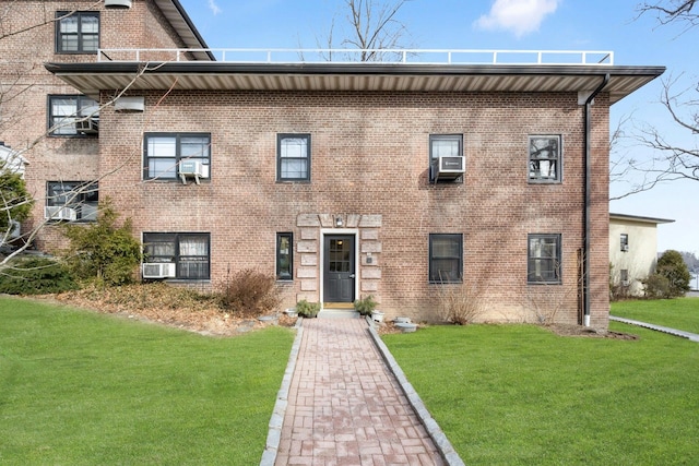 view of front of house with a front yard, brick siding, and cooling unit