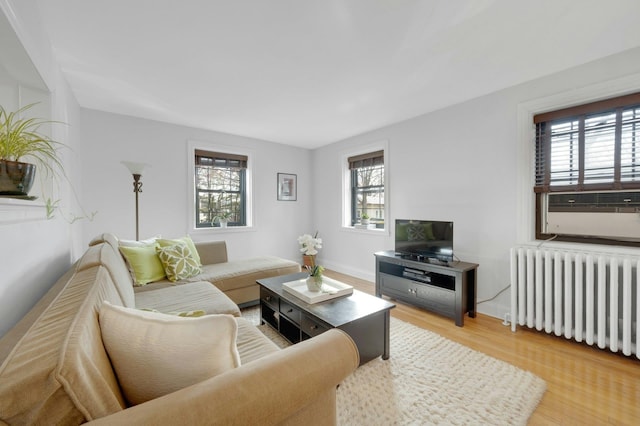 living area with radiator heating unit, baseboards, and light wood-style flooring