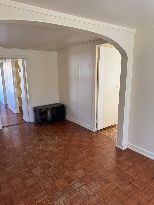 unfurnished room with arched walkways and baseboards