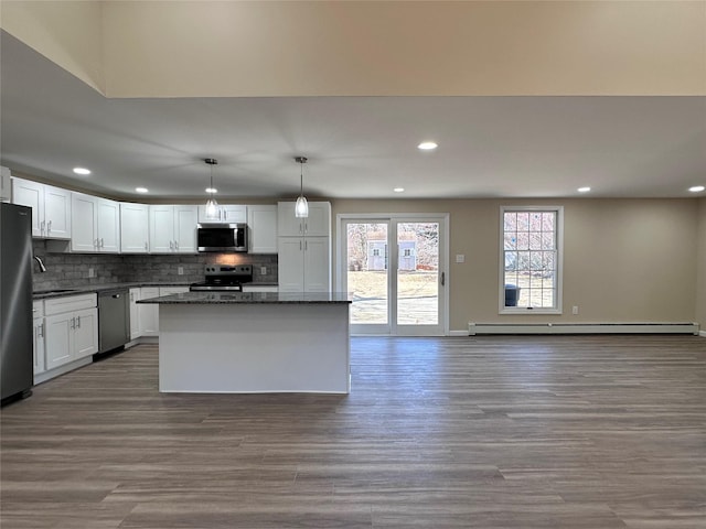 kitchen featuring a baseboard heating unit, stainless steel appliances, hanging light fixtures, and white cabinetry