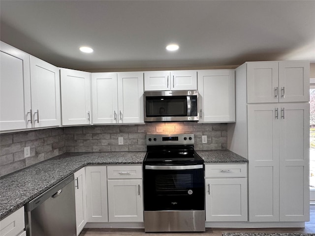 kitchen with white cabinetry, appliances with stainless steel finishes, tasteful backsplash, and dark stone countertops