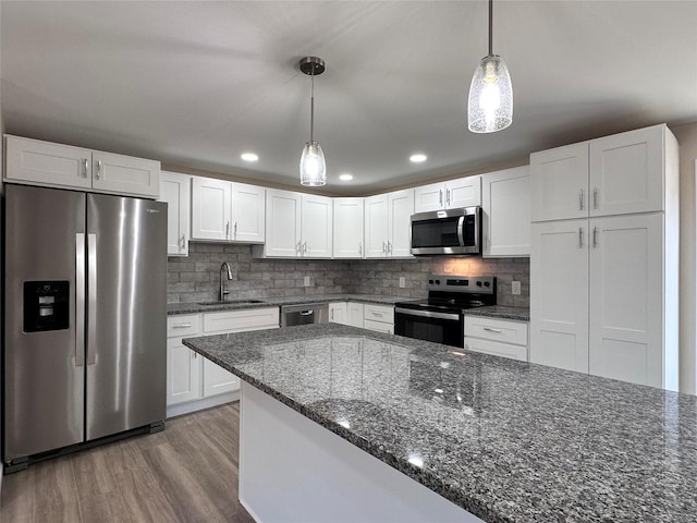 kitchen with stainless steel appliances, hanging light fixtures, a sink, and white cabinetry