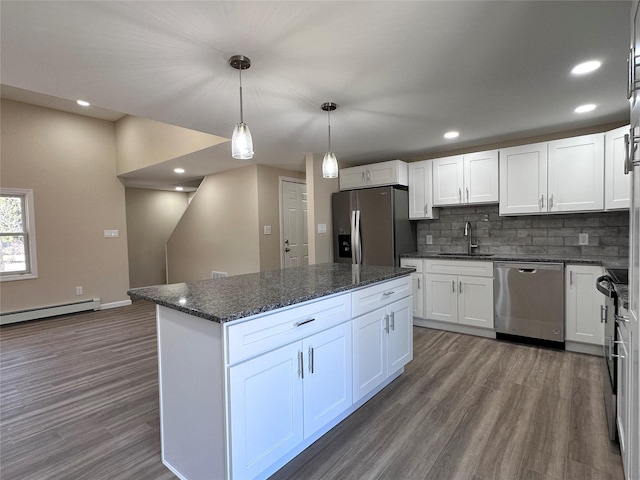 kitchen with white cabinets, decorative light fixtures, stainless steel appliances, a baseboard heating unit, and a sink