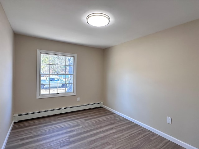 empty room with a baseboard radiator, baseboards, and wood finished floors