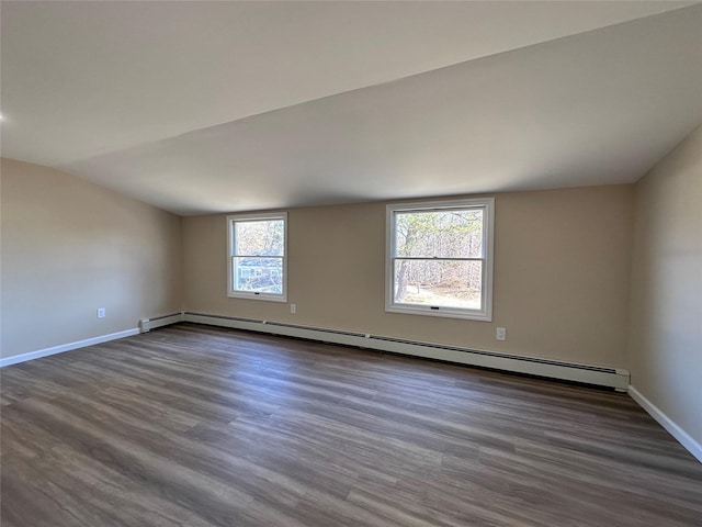 unfurnished room with dark wood finished floors, baseboards, vaulted ceiling, and baseboard heating