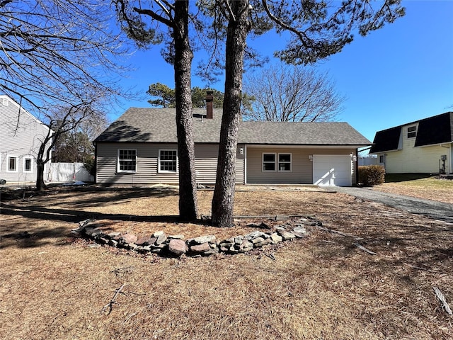 exterior space featuring a garage, roof with shingles, and driveway