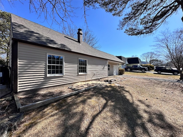 view of home's exterior featuring driveway and a chimney