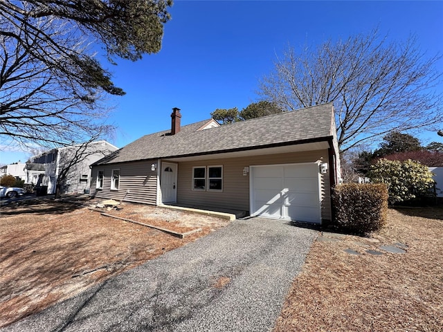 single story home with driveway, a shingled roof, a chimney, and an attached garage