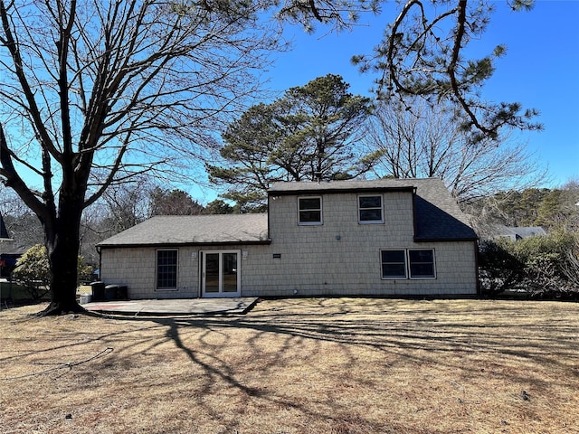 rear view of house featuring a shingled roof and a patio