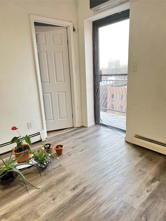 interior space featuring baseboard heating, light wood-type flooring, and a wall unit AC