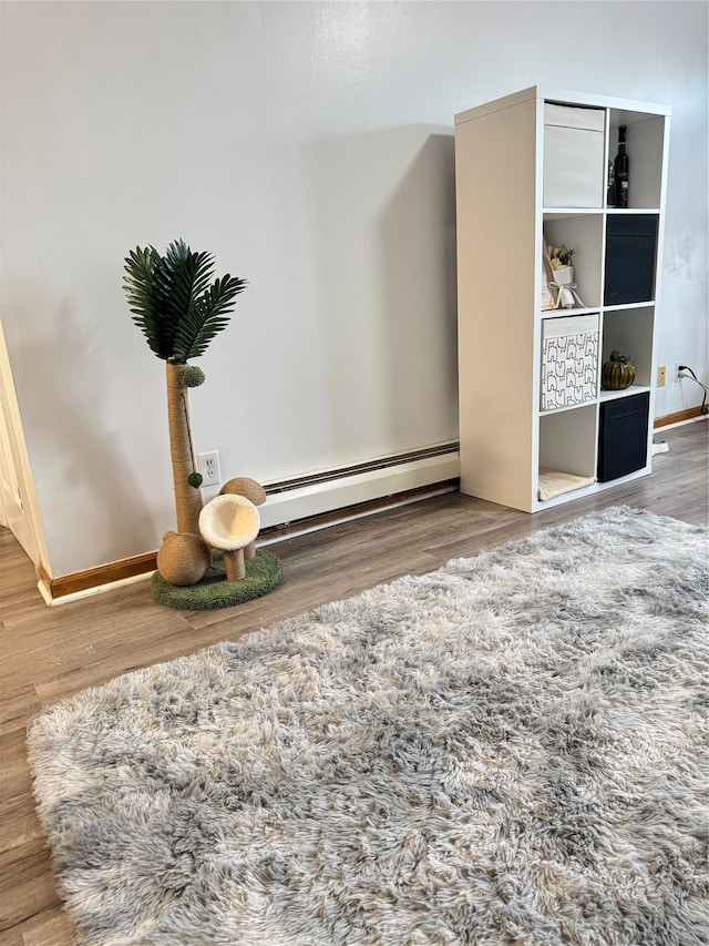 interior space featuring a baseboard radiator, baseboards, and wood finished floors