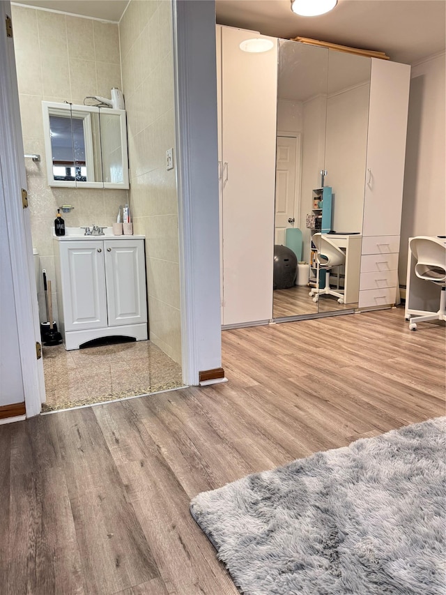 bathroom with wood finished floors, vanity, and tile walls