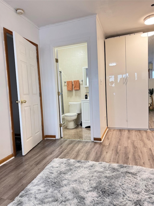 bedroom with baseboards, ornamental molding, and wood finished floors