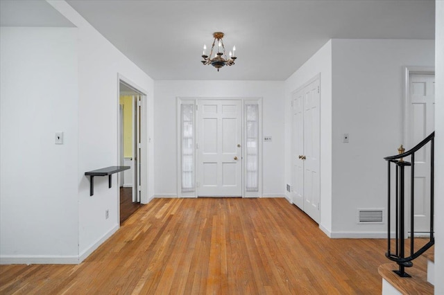 foyer entrance featuring baseboards, visible vents, light wood finished floors, and an inviting chandelier