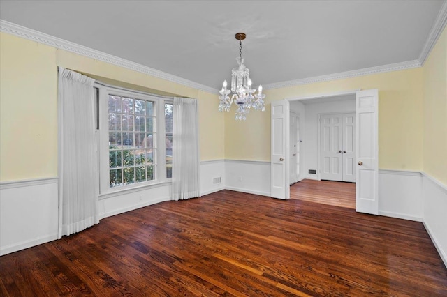 unfurnished dining area featuring a notable chandelier, crown molding, wood finished floors, and wainscoting