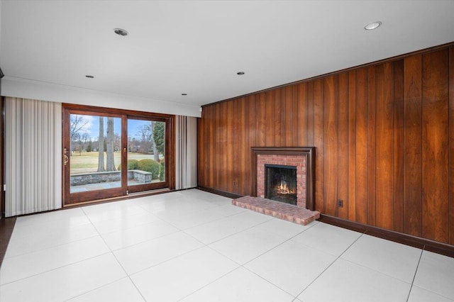 unfurnished living room featuring recessed lighting, a brick fireplace, light tile patterned flooring, and wooden walls