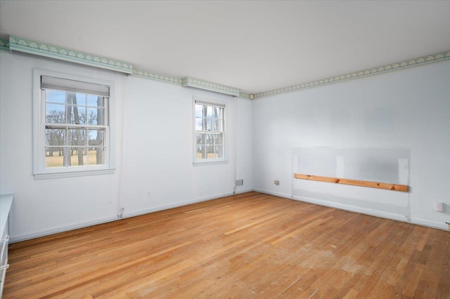 spare room with baseboards and light wood finished floors