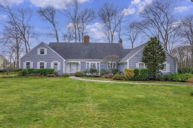 view of front of home with roof with shingles, a chimney, and a front yard