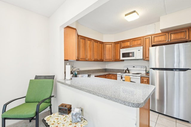 kitchen featuring a sink, a peninsula, white appliances, and light countertops