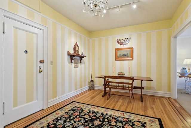 doorway featuring baseboards, wood finished floors, and wallpapered walls