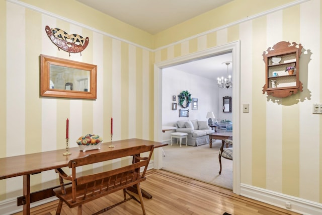 interior space with wallpapered walls, baseboards, a chandelier, and wood finished floors