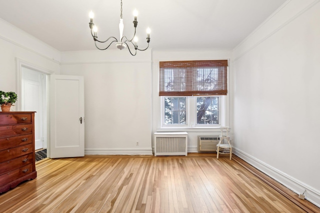 unfurnished dining area with a wall unit AC, a notable chandelier, baseboards, light wood-style floors, and radiator