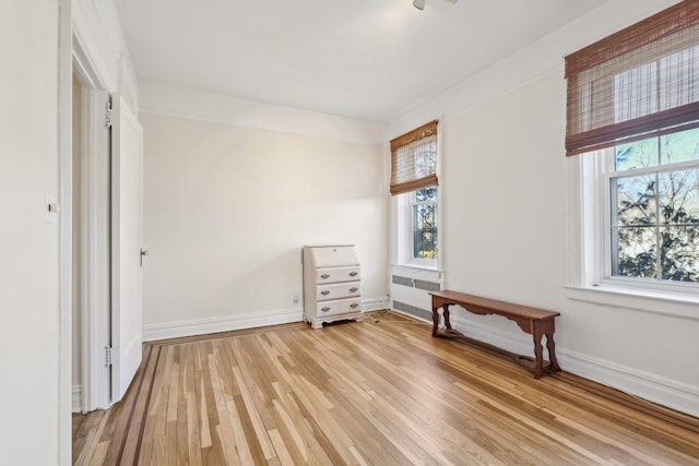 unfurnished bedroom featuring light wood-style flooring, multiple windows, and baseboards