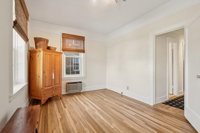 unfurnished room featuring baseboards, an AC wall unit, and wood finished floors