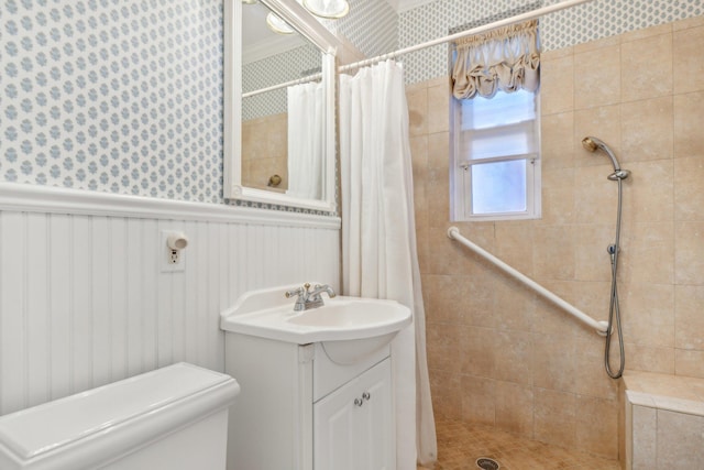 full bath with toilet, a shower stall, vanity, and wainscoting