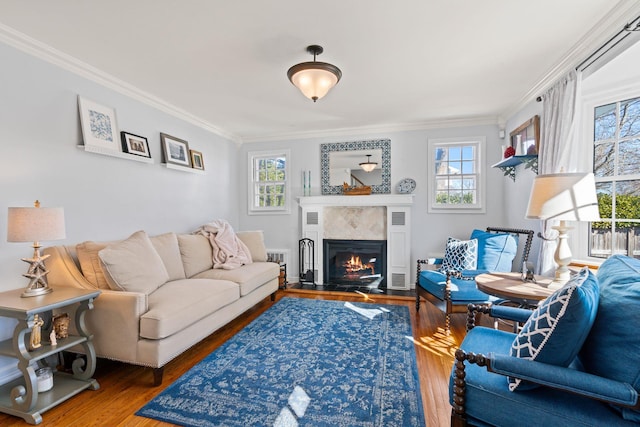 living room with a warm lit fireplace, crown molding, a wealth of natural light, and wood finished floors