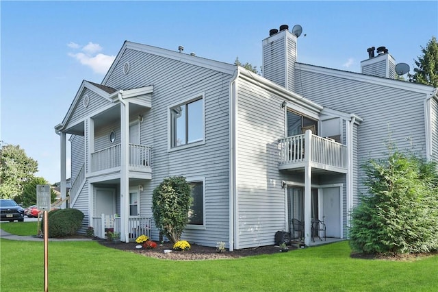 view of home's exterior with a yard, a chimney, cooling unit, and a balcony