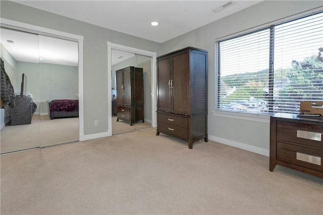 bedroom with recessed lighting, light carpet, visible vents, baseboards, and two closets