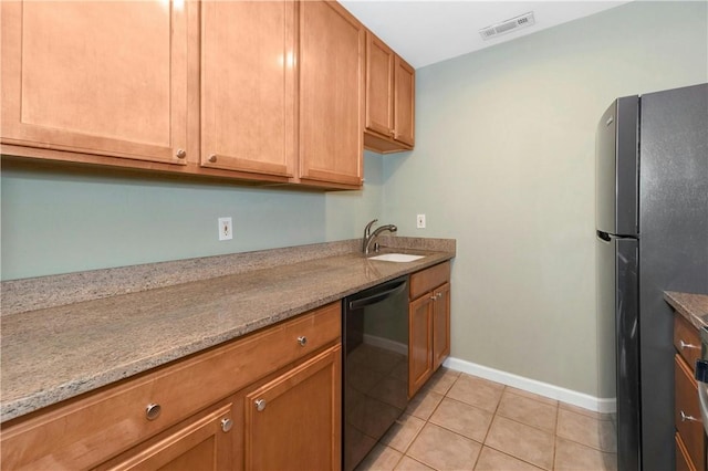 kitchen with a sink, visible vents, black dishwasher, freestanding refrigerator, and light stone countertops