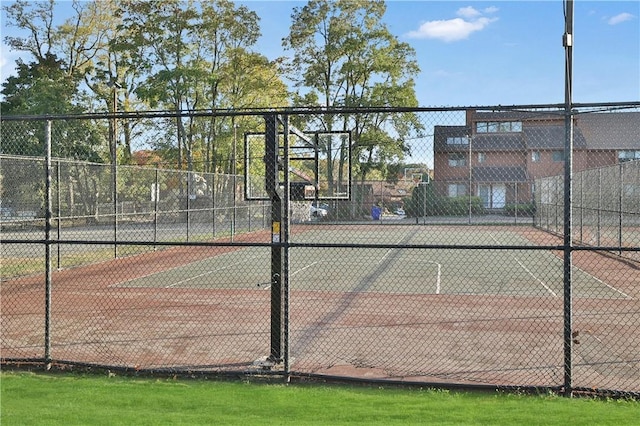 view of tennis court with community basketball court and fence