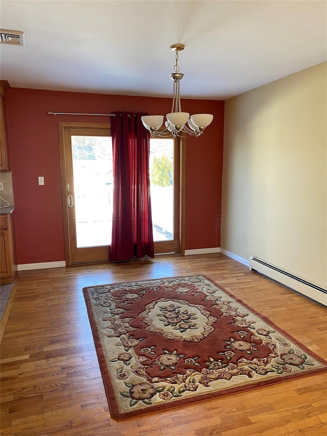 doorway featuring light wood-style floors, a baseboard radiator, visible vents, and baseboards