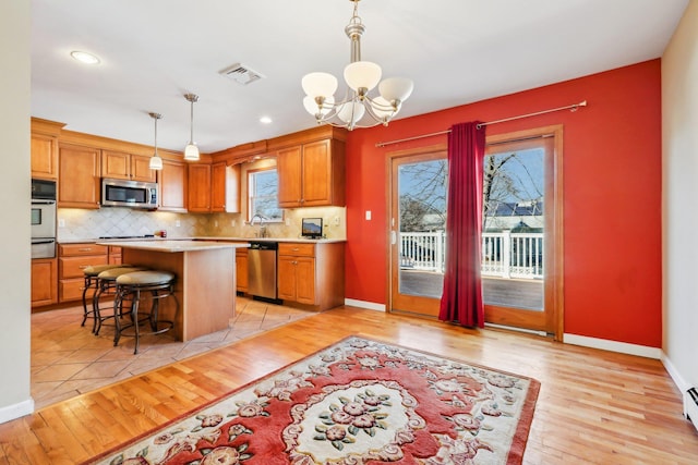 kitchen featuring stainless steel appliances, backsplash, light countertops, and visible vents