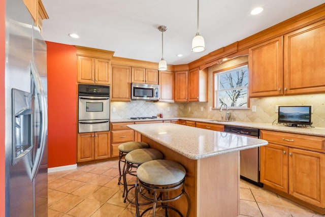 kitchen with a breakfast bar, a center island, light tile patterned floors, stainless steel appliances, and a sink