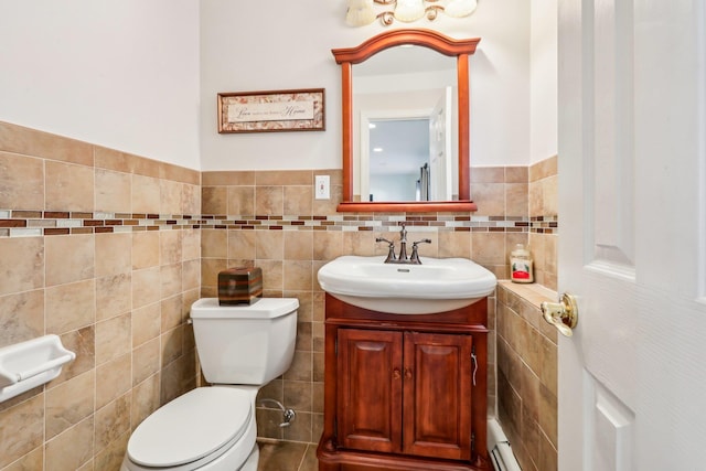 half bathroom with toilet, baseboard heating, tile walls, and vanity