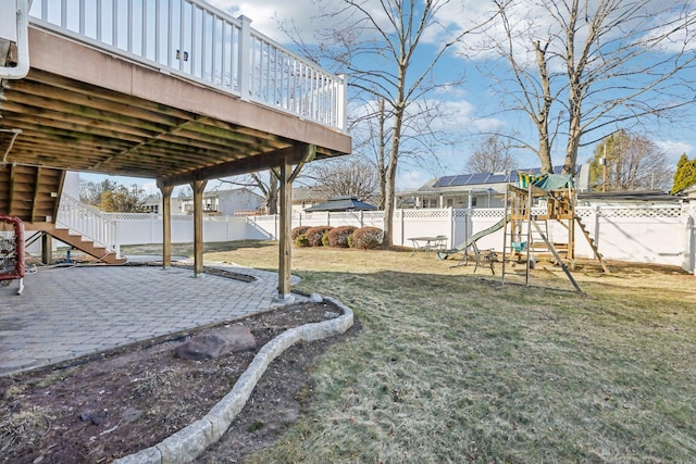 view of yard featuring a patio area, a playground, a fenced backyard, and stairs