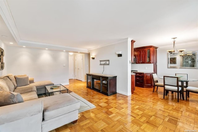 living room with baseboards, ornamental molding, a notable chandelier, and recessed lighting