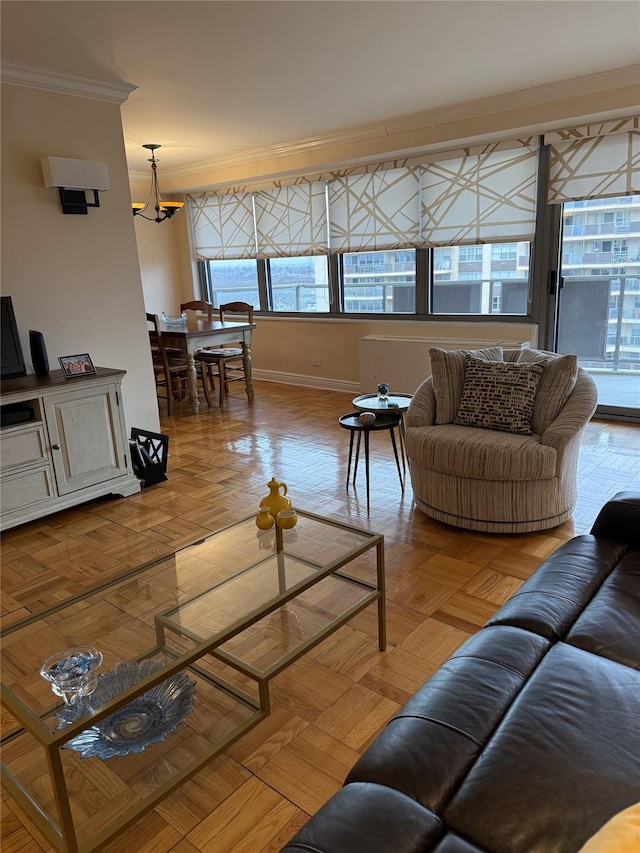 living room featuring baseboards, ornamental molding, and a notable chandelier