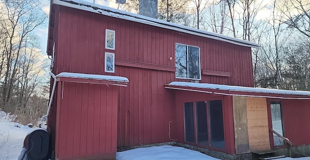 view of snow covered exterior featuring metal roof and a chimney