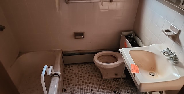 bathroom with toilet, a tub to relax in, tile walls, and a sink