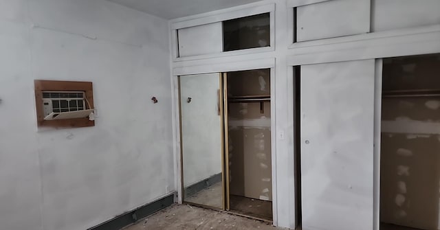 unfurnished bedroom with multiple closets and an AC wall unit