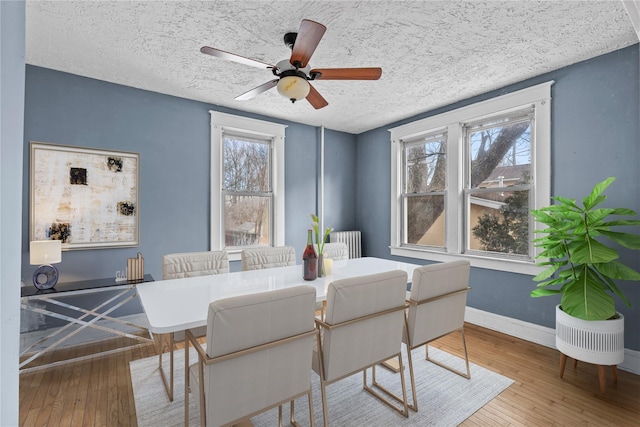 dining room with baseboards, a ceiling fan, radiator heating unit, wood finished floors, and a textured ceiling