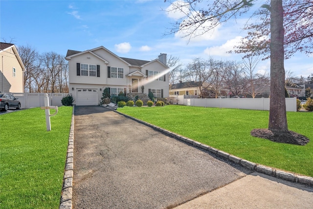 view of front of property with a front yard, a chimney, fence, and driveway