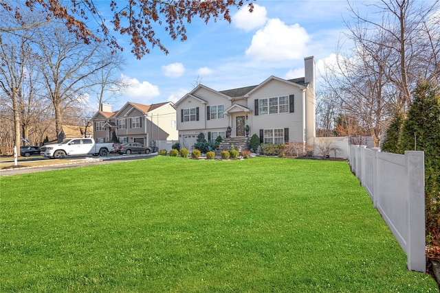 split foyer home with a front lawn, a chimney, fence, and a residential view