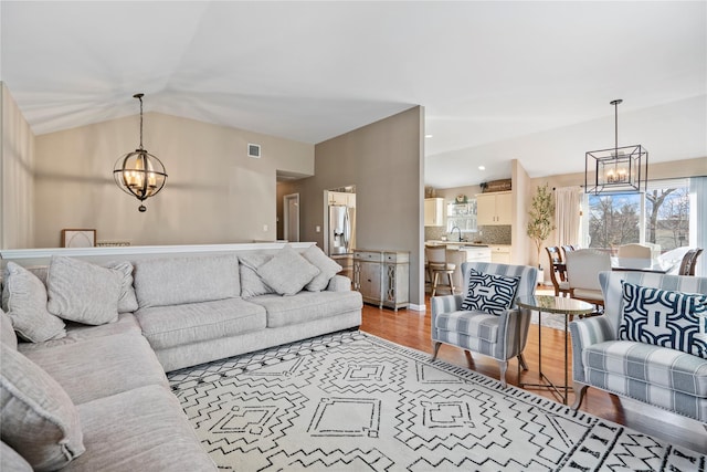 living area with a chandelier, lofted ceiling, light wood-style flooring, recessed lighting, and visible vents