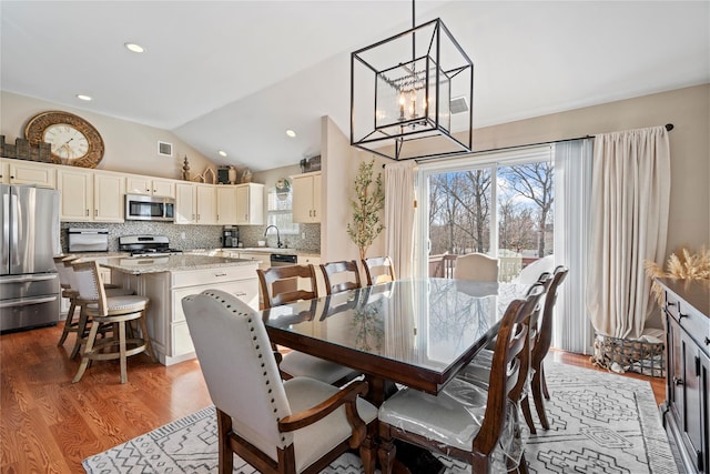 dining room with visible vents, lofted ceiling, wood finished floors, an inviting chandelier, and recessed lighting