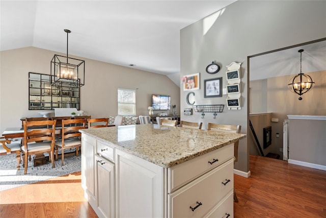 kitchen with vaulted ceiling, wood finished floors, and an inviting chandelier